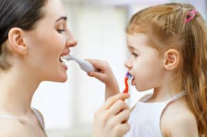 Mother and daughter brushing each other's teeth