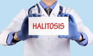Doctor holding a sign that says "halitosis"