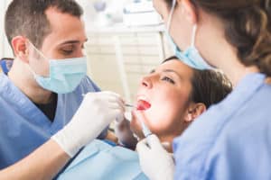 Woman having her teeth looked at by a dentist and hygienist