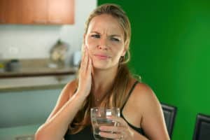woman drinking water that has tooth pain