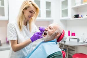 Dental hygienist helping an older man with his dental work