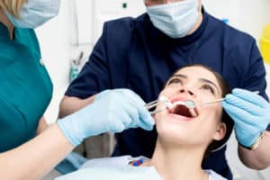 Young woman receiving a dental cleaning from a dental hygienist and dentist