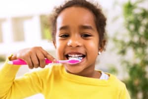 Young female child brushing her teeth and smiling. 