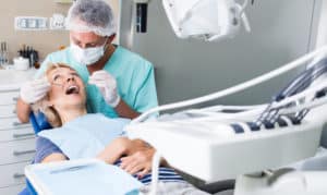 A dentist doing dental work on a middle-aged woman in a dental office.