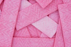 Sticks of pink chewing gum that are all stacked on top of each other. 