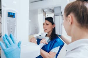 A brunette woman patient in a dental office that is having her dental x-rays done with a Dental Cone Beam CT machine.