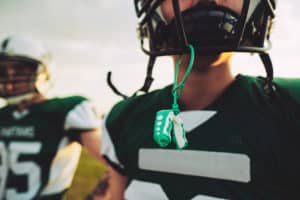 A close-up view of a young adult male that is wearing football gear and a mouthpiece that protects his teeth.