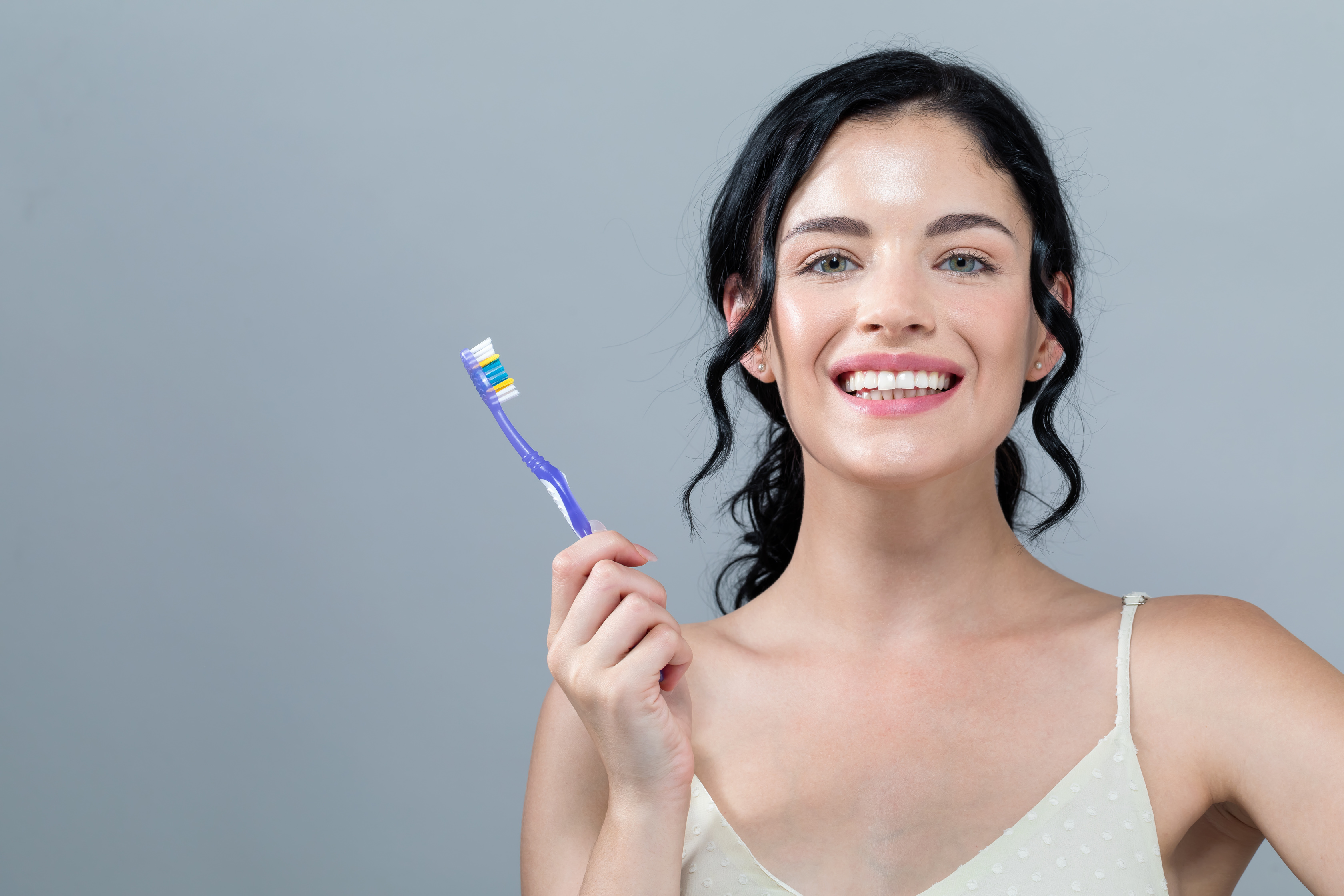 Young woman holding a toothbrush - Dr Ania Mohelicki Site