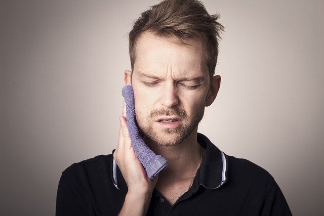 Man in pain holding his cheek with hand, suffering from bad tooth ache