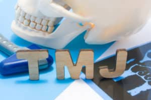 TMJ letters surrounded by human skull with lower jaw