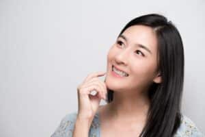 Asian woman smiling and wearing an orthodontic retainers.