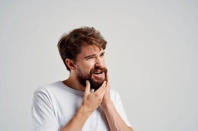 A man with TMJ holding his jaw