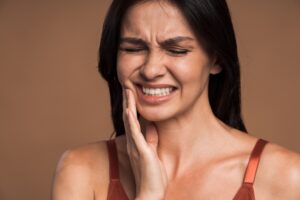 Woman with jaw pain holding her jaw